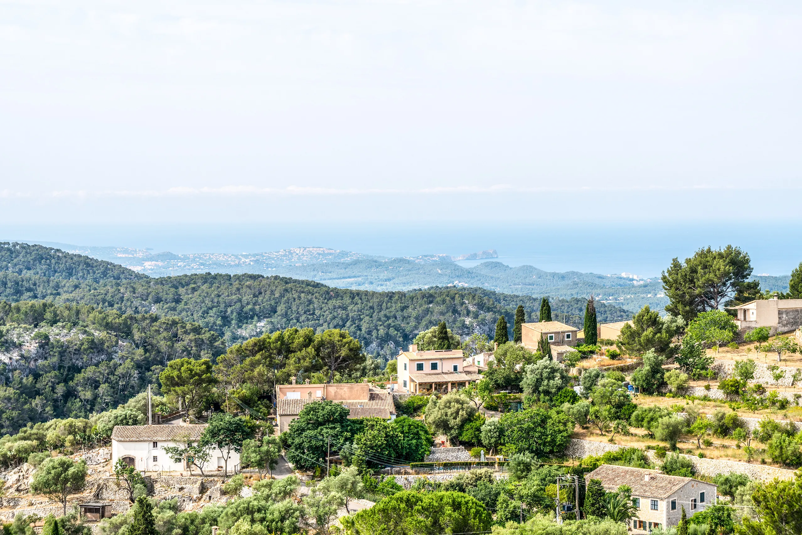Weiter Blick von Galilea über bewaldete Hügel und verstreute Häuser hinunter zur Ebene und zum Meer am Horizont.
