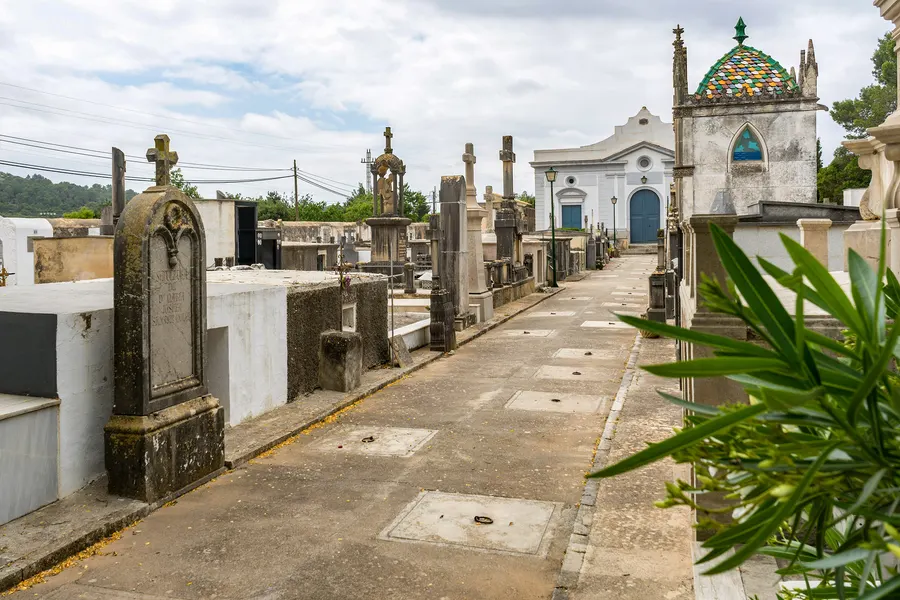 Reihe aufwendig gestalteter Grabkapellen mit farbigen Kuppeln auf dem Friedhof von Alaró unter blauem Himmel.
