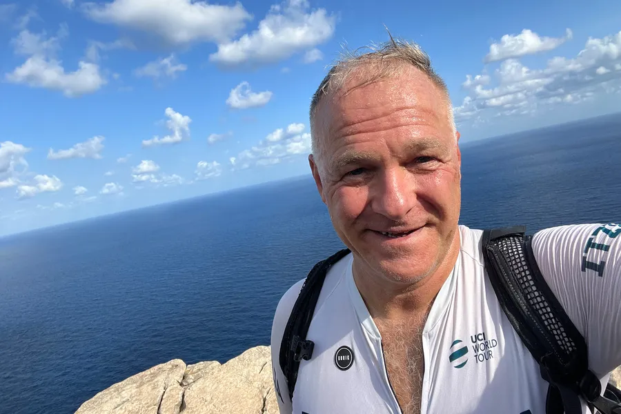 Friedhelm Fischer im Radtrikot auf dem Fels am Cap de Formentor, dahinter das offene Meer unter blauem Himmel.
