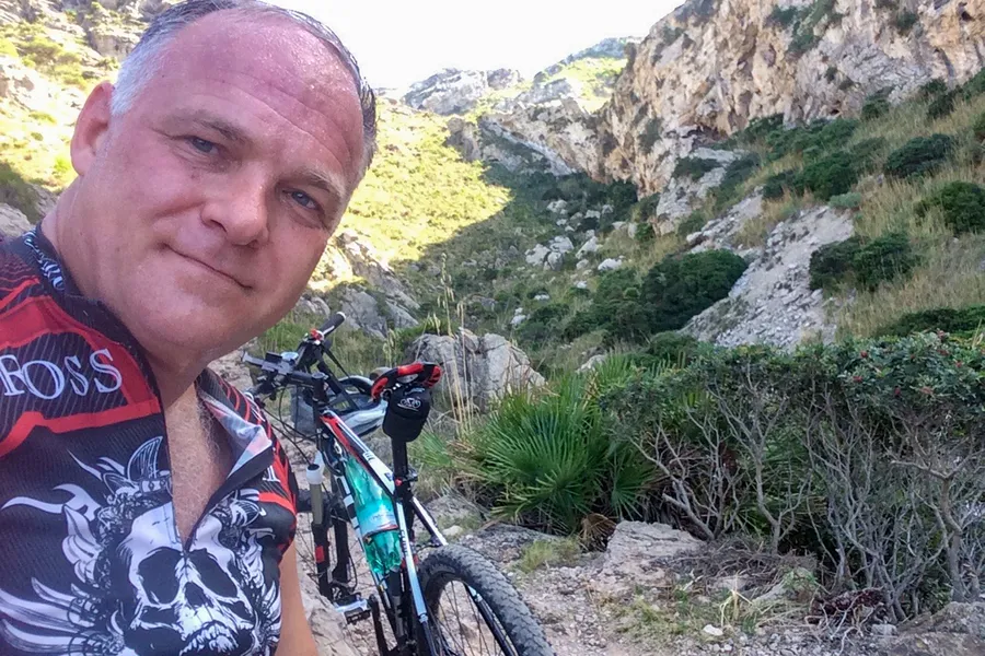 Friedhelm Fischer im Radtrikot neben seinem Mountainbike auf einem steinigen Weg im Massís d'Artà auf dem Weg zur Ermita de Betlem.