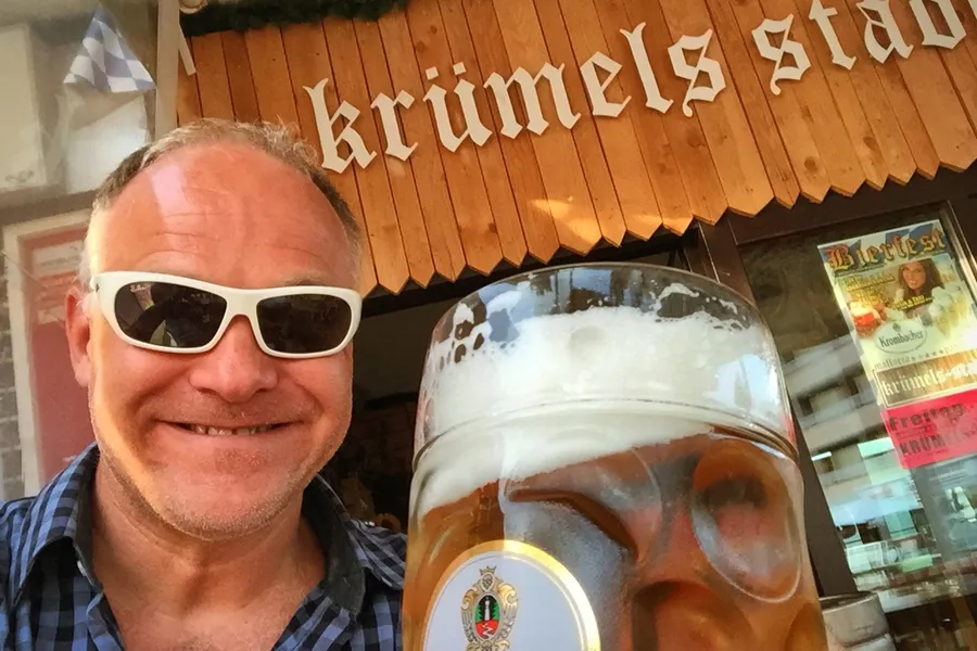 Friedhelm Fischer mit weißer Sonnenbrille und einer Maß Bier vor dem Lokal Krümels Stadl in Peguera.