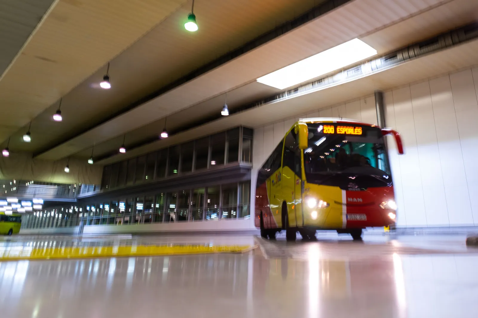 Ein gelb-roter Linienbus des TIB in der unterirdischen Bushalle der Estació Intermodal in Palma.
