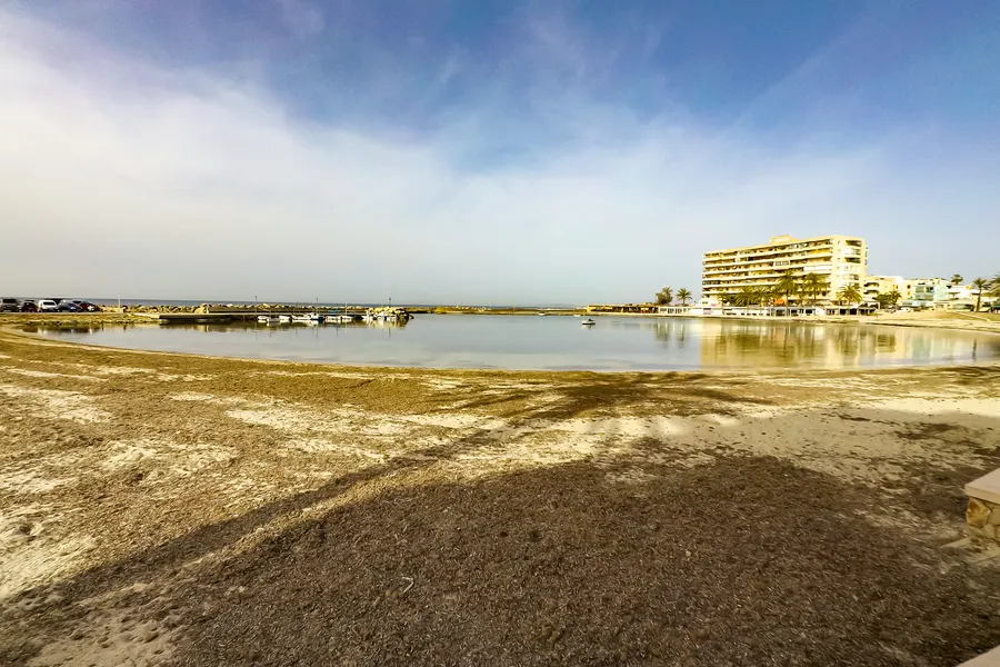 Der Beginn der Playa de Palma bei Can Pastilla mit hellem Sand, flachem Wasser und Hotelbauten am hinteren Strandrand.