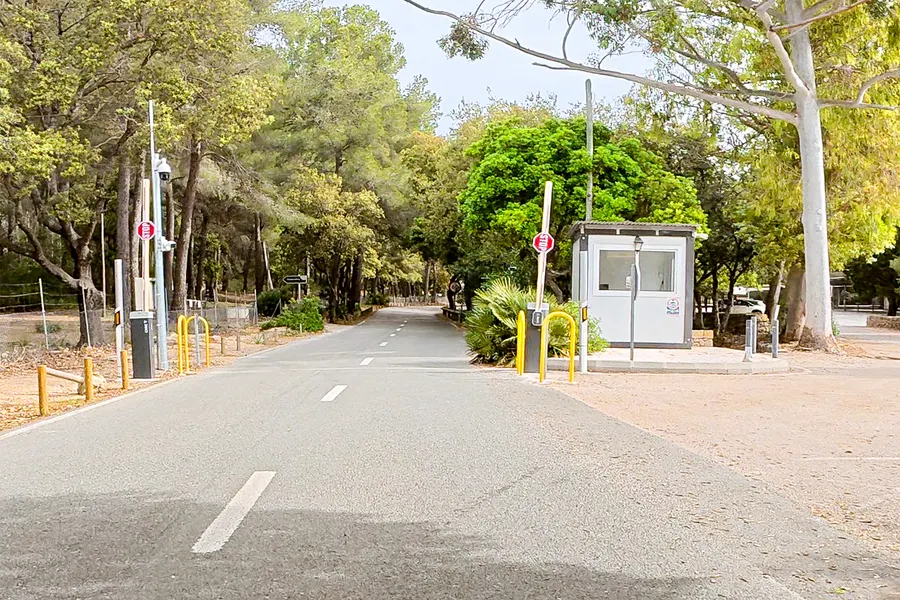 Kontrollhäuschen mit Schranke und Kameramast an der Zufahrt bei der Platja de Formentor, Einfahrt-verboten-Schilder am Straßenrand.
