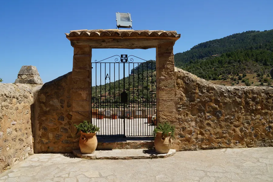 Kleiner Laden in einem Natursteinhaus in Deià mit Korbstühlen, Pflanzkübeln und einem Schild über der Tür.
