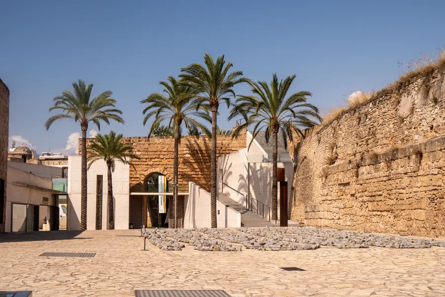 Innenhof des Museums Es Baluard in Palma mit Palmen, hellem Boden und der Festungsmauer als Abschluss.

