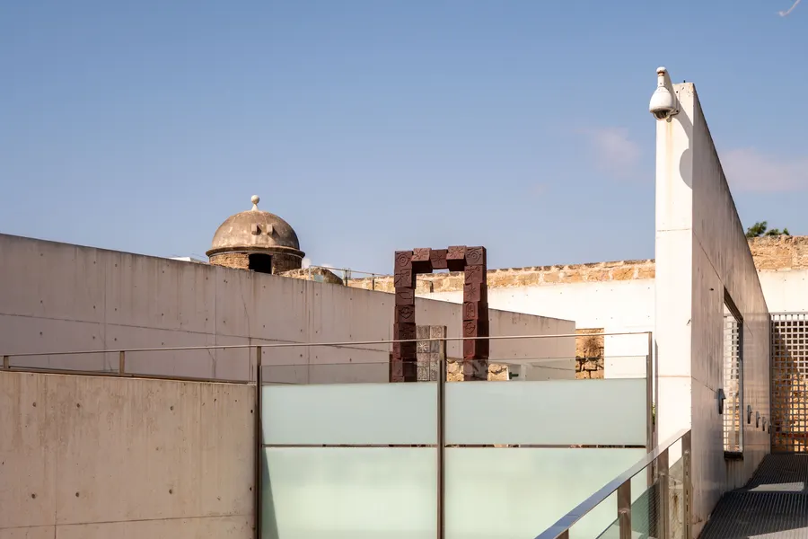 Terrasse des Museums Es Baluard mit Glasgeländer, Betonflächen und dem gemauerten Wachturm der Bastion.

