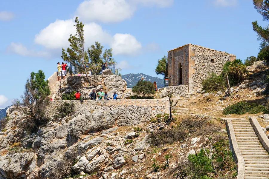 Bruchsteinhäuschen auf dem Felskopf des Mirador de Ricardo Roca, davor Besucher an der Brüstung und eine Trockenmauer.
