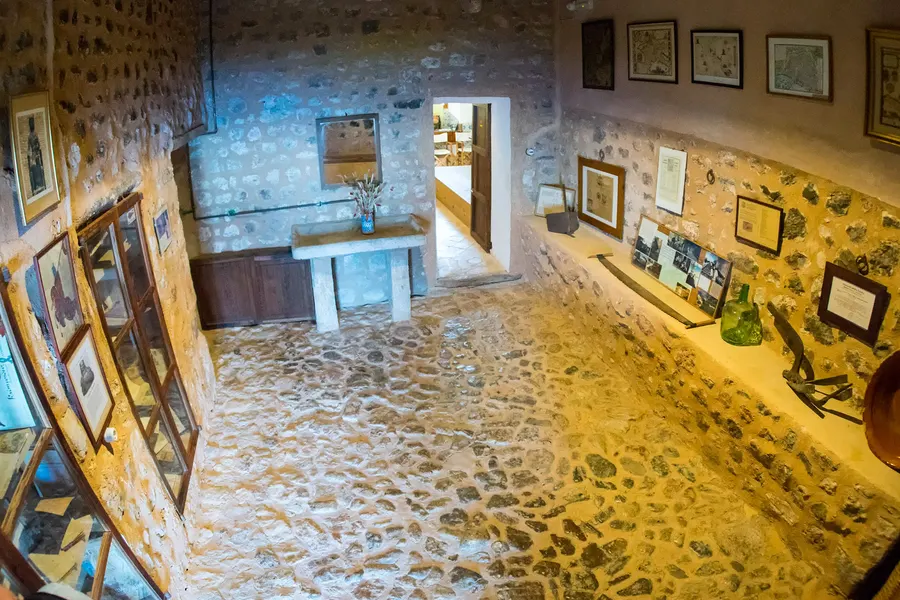 Ausstellungsraum in Miramar mit gerahmten Bildern und Dokumenten an den Natursteinwänden und einem gepflasterten Boden.
