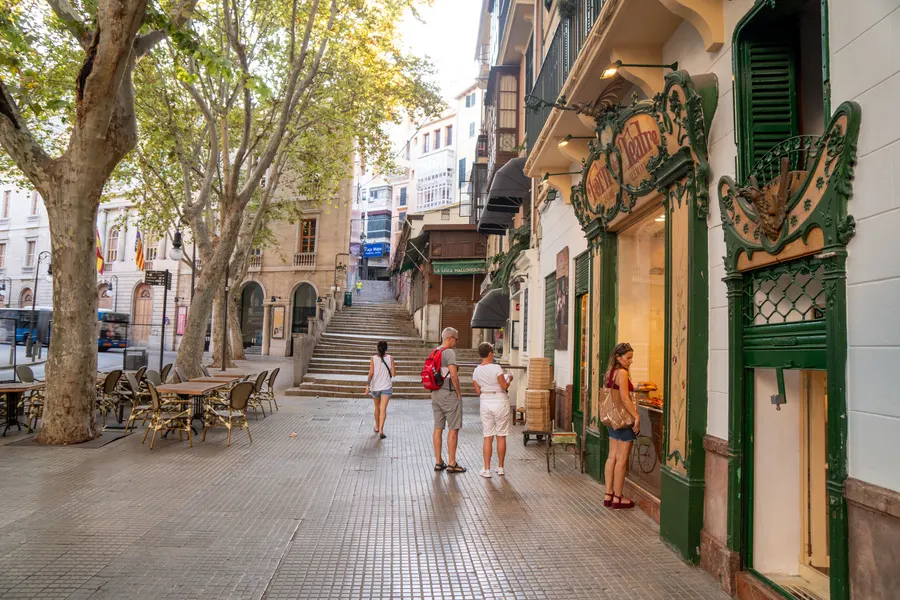 Blick die ansteigende Gasse an der Plaça de Weyler in Palma hinauf, rechts die Jugendstilfassade der Bäckerei Forn des Teatre.
