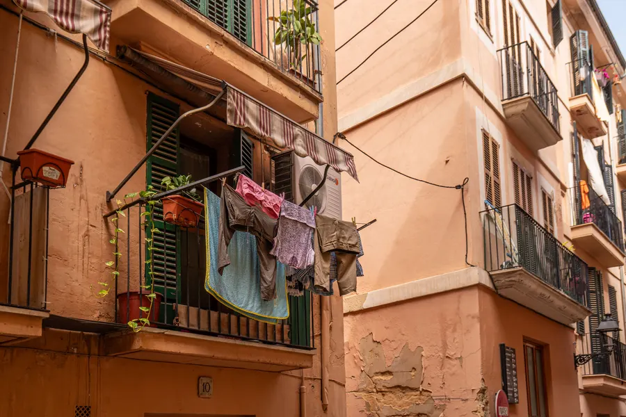 Wäsche hängt an einem Balkon über einer engen Gasse in Palmas Altstadt, die Fassaden sind ockerfarben.
