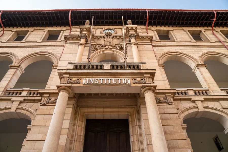 Die klassizistische Hauptfassade des Gymnasiums IES Ramon Llull in Palma mit Säulenportal und der Aufschrift Instituto.
