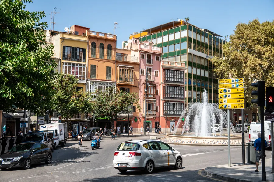 Verkehr auf der Plaça de la Reina in Palma, im Hintergrund der Springbrunnen und ein Wegweiser Richtung Born.