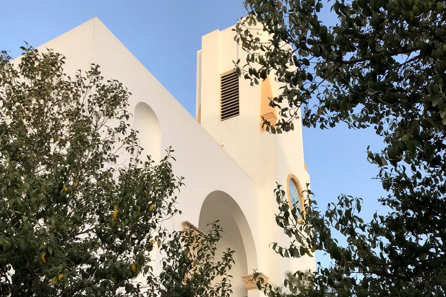 Hölzerner Rettungsschwimmerturm am leeren Winterstrand der Platja de Palma unter bewölktem Himmel, dahinter die Berge.

