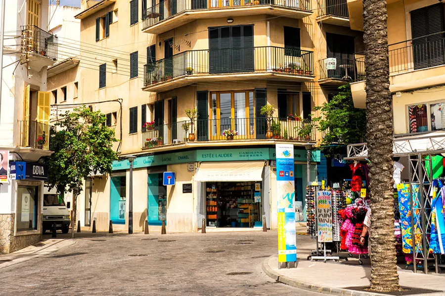 Eckladen mit Souvenirs, Handtüchern und Strandartikeln in Porto Cristo, davor die leere Straßenkreuzung.
