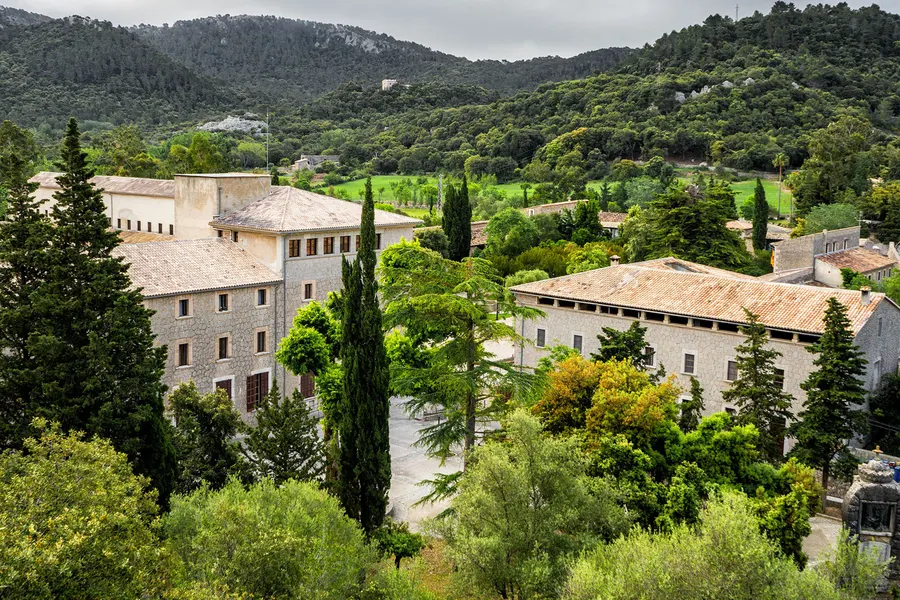 Die Klosteranlage von Lluc zwischen Zypressen und bewaldeten Hängen der Serra de Tramuntana.
