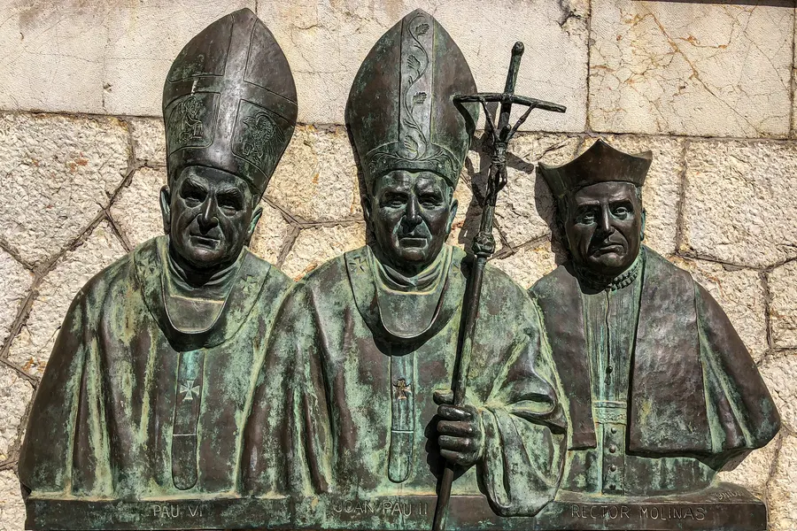 Bronzerelief mit drei geistlichen Figuren in Mitren und mit Bischofsstab an einer Natursteinmauer in Sencelles.