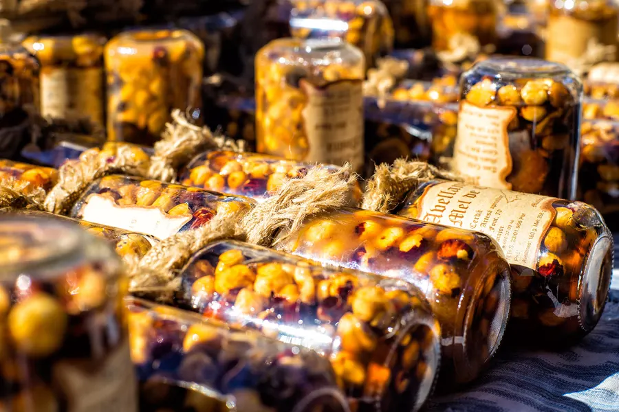 Reihen liegender Einmachgläser mit eingelegten Früchten und Gemüse in Öl auf einem Marktstand in Sineu.
