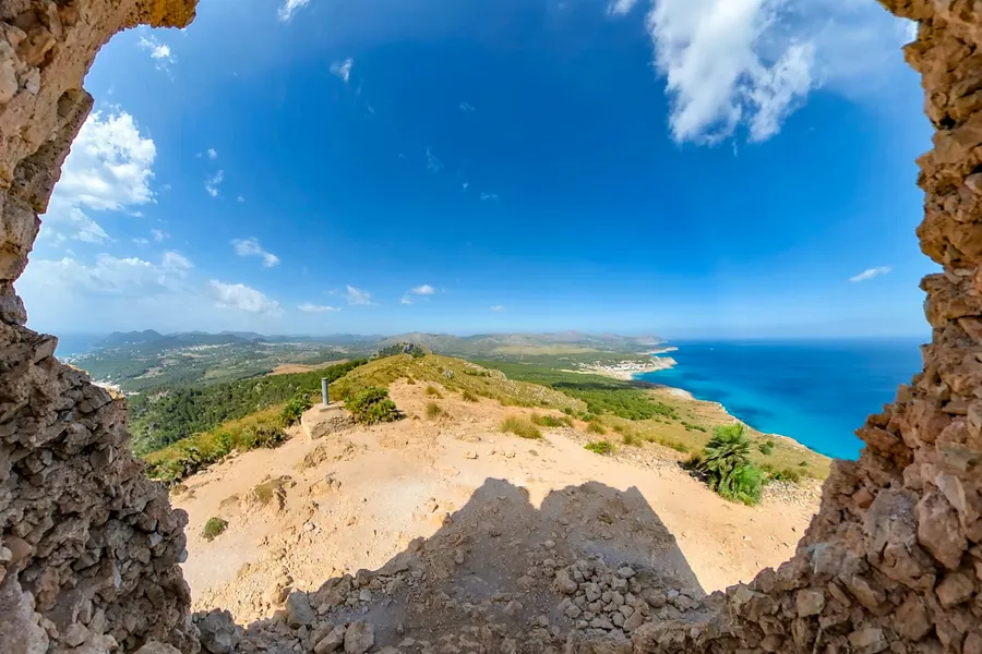 Blick durch eine Maueröffnung des Wachturms hinaus auf den kahlen Bergrücken, die Küste und das offene Meer.