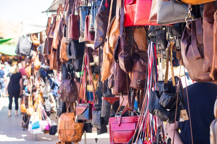 Dicht behängter Stand mit Lederimitat-Taschen in vielen Farben entlang einer Marktgasse in Alcúdia.